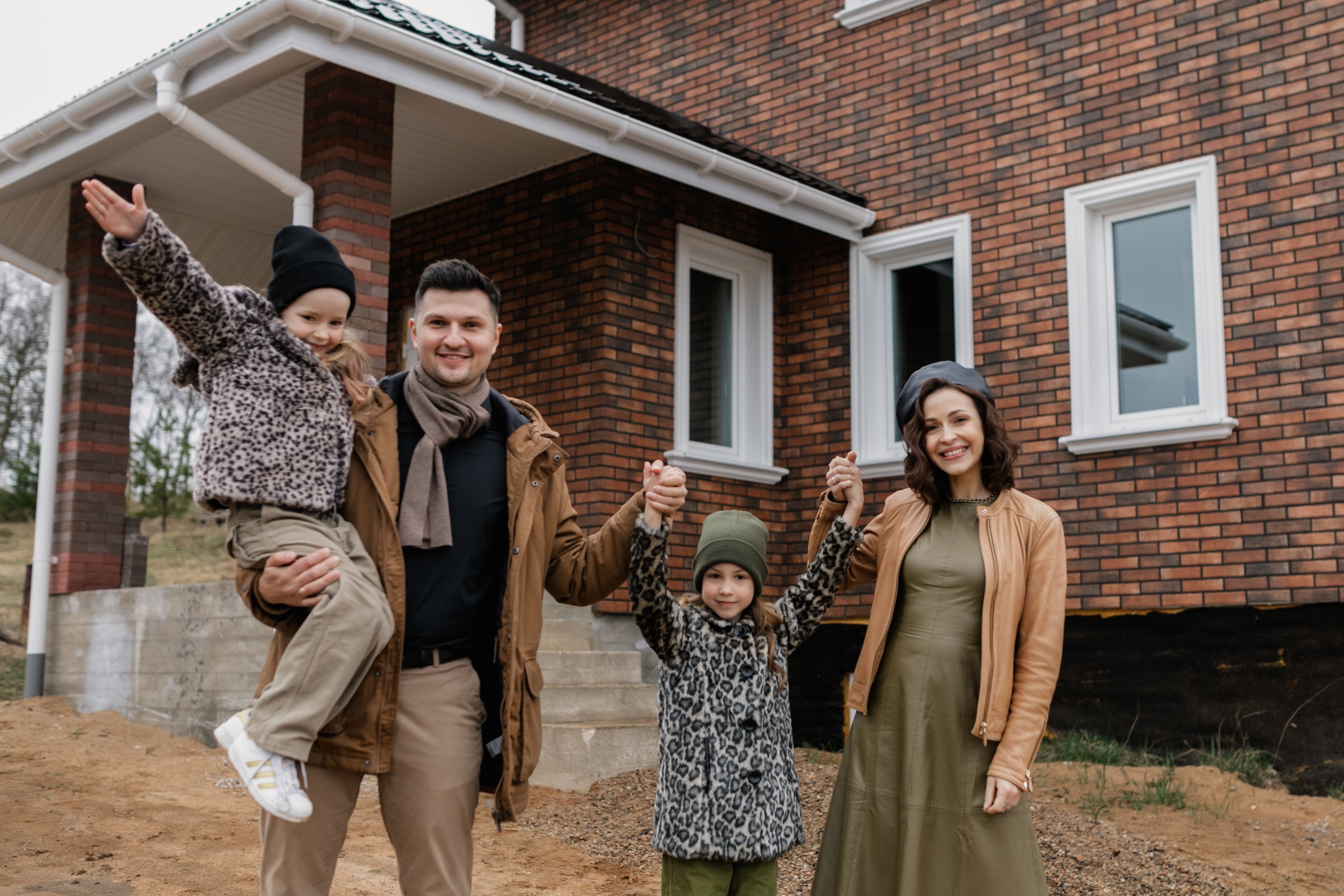 A family holding hands in front of their new home